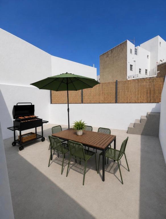 a table and chairs with an umbrella and a grill at Patio del recuerdo in Benalup Casas Viejas