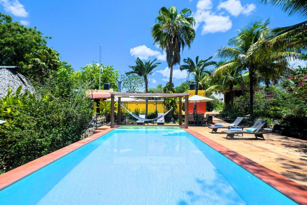 ein Swimmingpool mit Stühlen und einem Pavillon in der Unterkunft The Pickled Onion Hotel & Restaurant Uxmal in Santa Elena