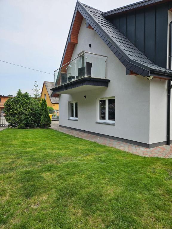 a white house with a balcony and a yard at Zakątek przy Wydmie in Dziwnów