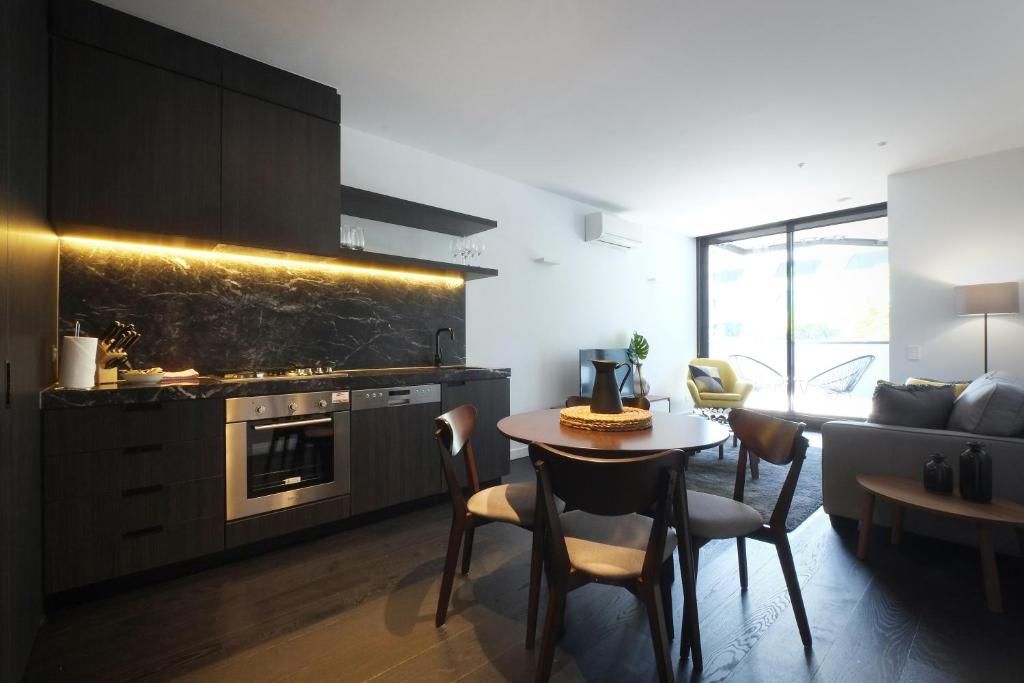 a kitchen and living room with a table and a couch at Turnkey Accommodation-North Melbourne in Melbourne