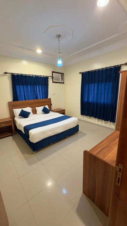 a bedroom with a large bed with blue curtains at غيوم ابها - شقق مخدومه in Abha