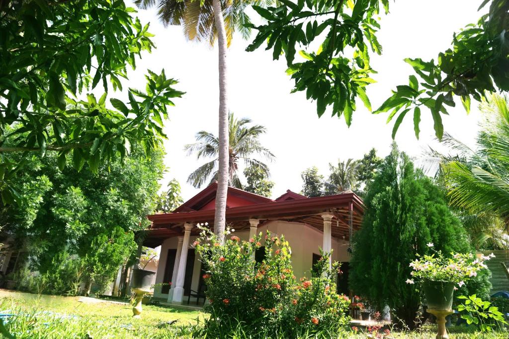 a house in the middle of a garden with palm trees at New Vilard in Tissamaharama