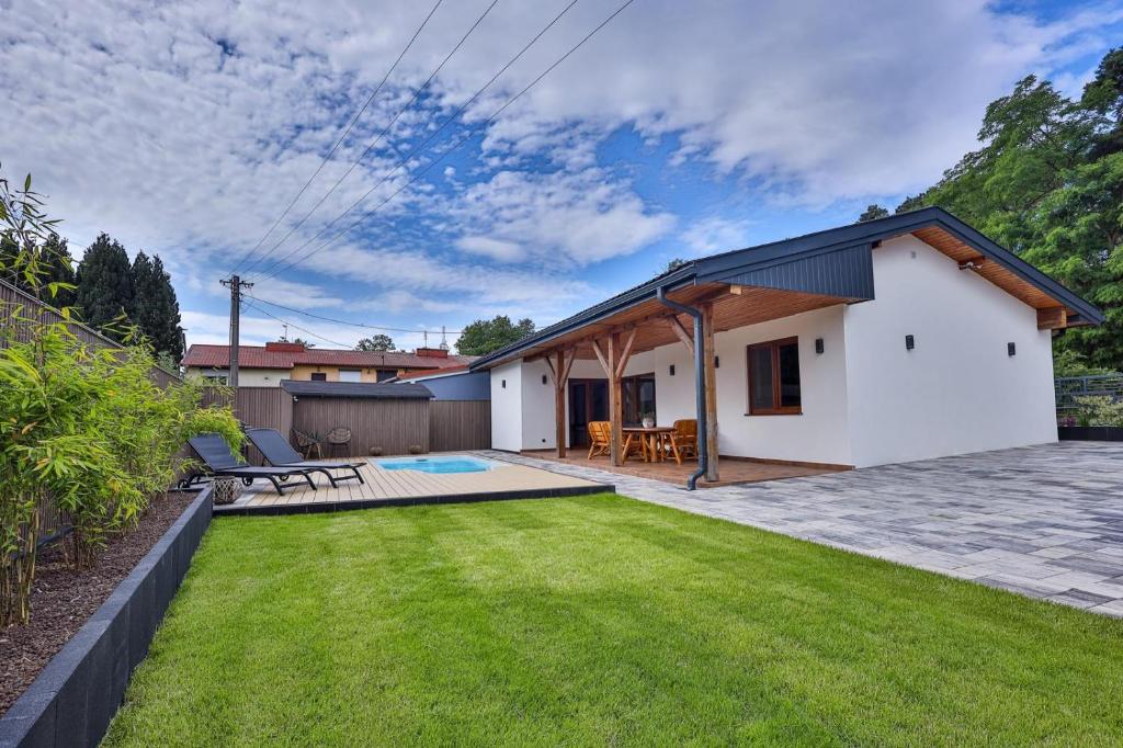 a white house with a patio and a yard at BOSzKO HOUSE in Boszkowo