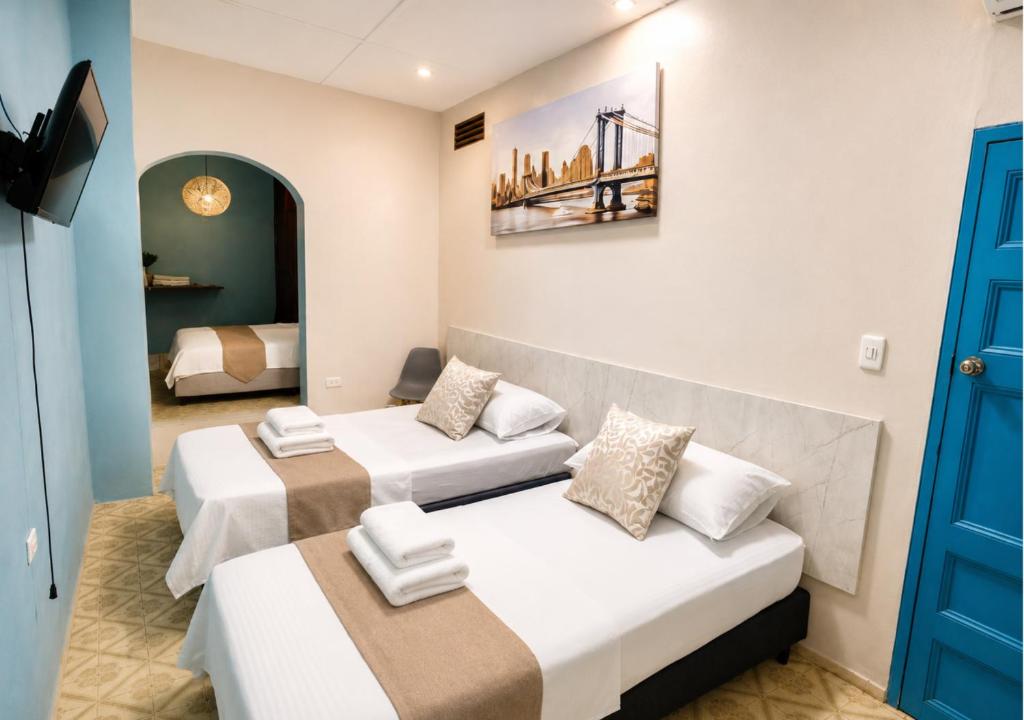a room with two beds and a blue door at Hotel Kasaya Grand Deluxe in Santa Marta