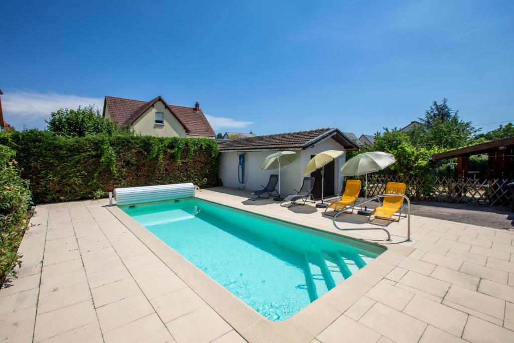 a swimming pool with two chairs and two umbrellas at -New- Colmar, Parking, Comfort, Spacious in Ingersheim