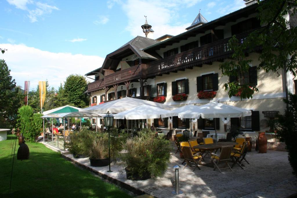 ein Gebäude mit Tischen und Sonnenschirmen davor in der Unterkunft Hotel Stroblerhof in Strobl