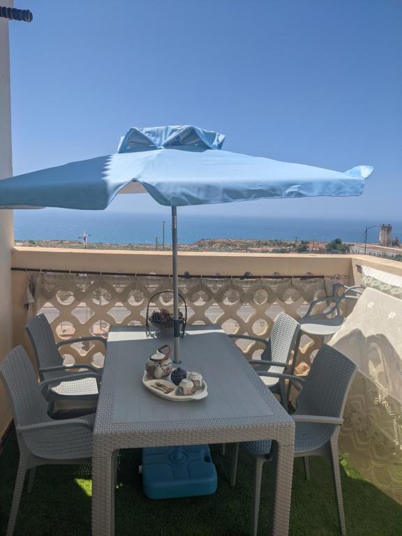 a table with a blue umbrella on a balcony at Mostaganem kharrouba apartment f3 in Mostaganem