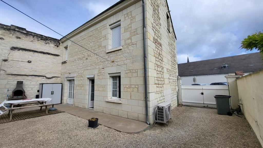 a large brick building with a grill in a courtyard at Centre Bourg d'Avoine Cottage in Avoine