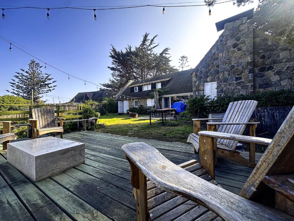 a deck with wooden chairs and a bench and a table at Casona IslaNegra in Isla Negra