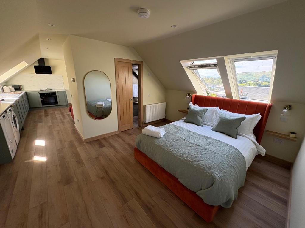 a bedroom with a large bed and a kitchen at Coorie-Tigh in Connel