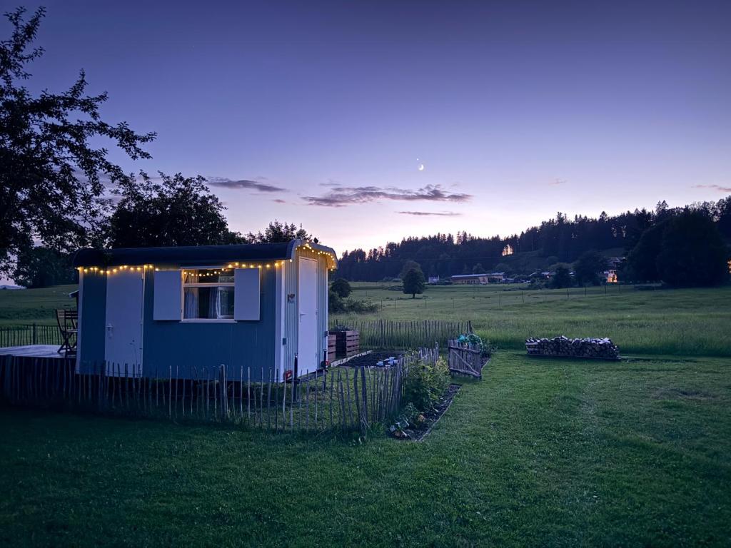 a tiny house with lights on it in a field at Genau So - Schäferwagen in Maierhöfen