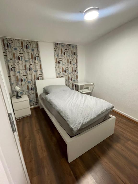 a bedroom with a white bed and a wooden floor at Haus zum Bacchus Privatezimmer near Bahnhof Römisches Theater Mainz in Mainz