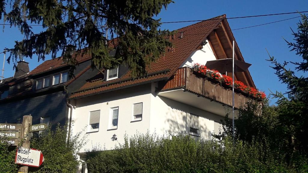 a white building with a balcony with flowers on it at Lausebuche Im Sauerland in Lennestadt