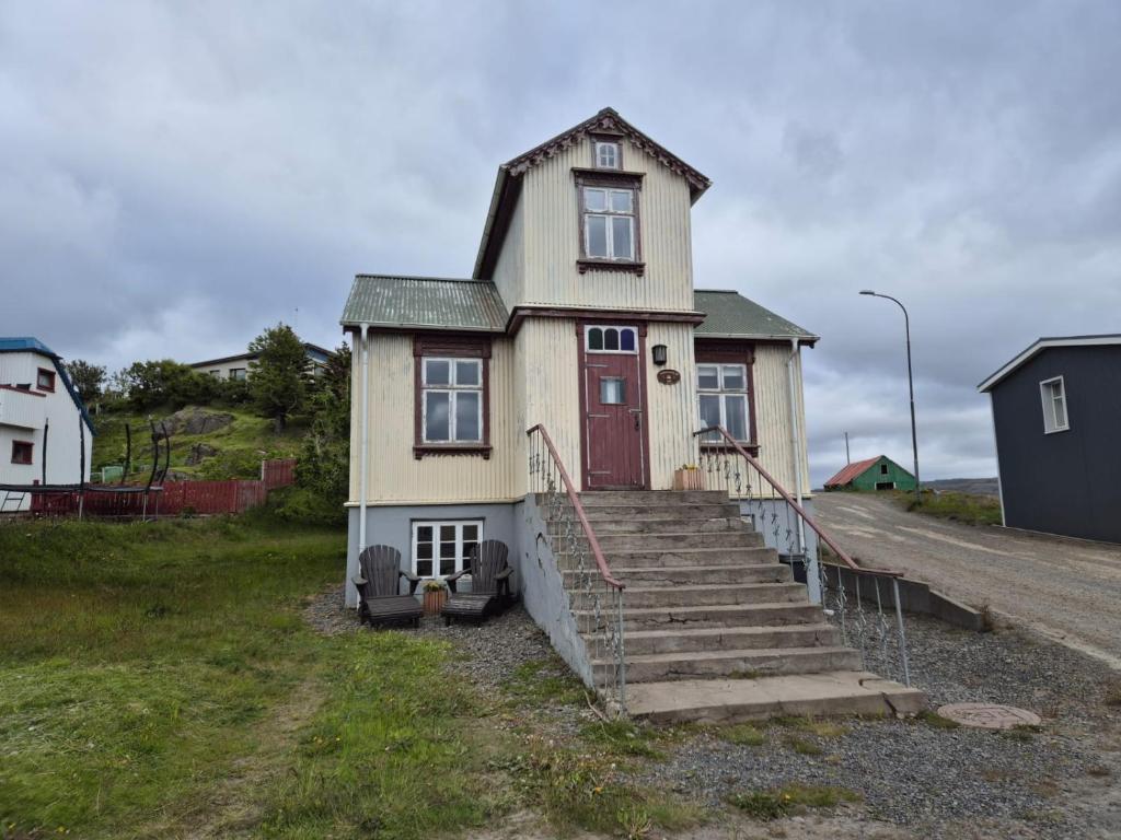 a small house with a red door and stairs at Steinhúsið in Hólmavík