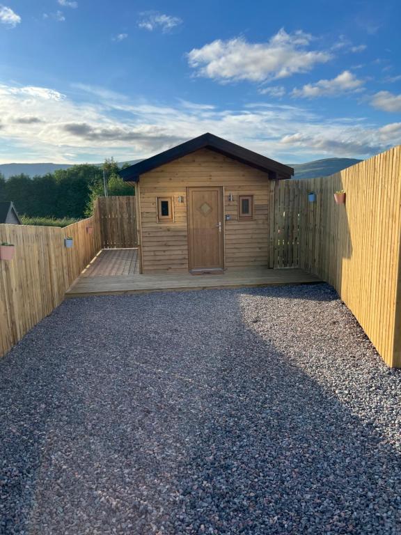 a wooden building with a door on a fence at Jacobite Cabin in Inverlochy