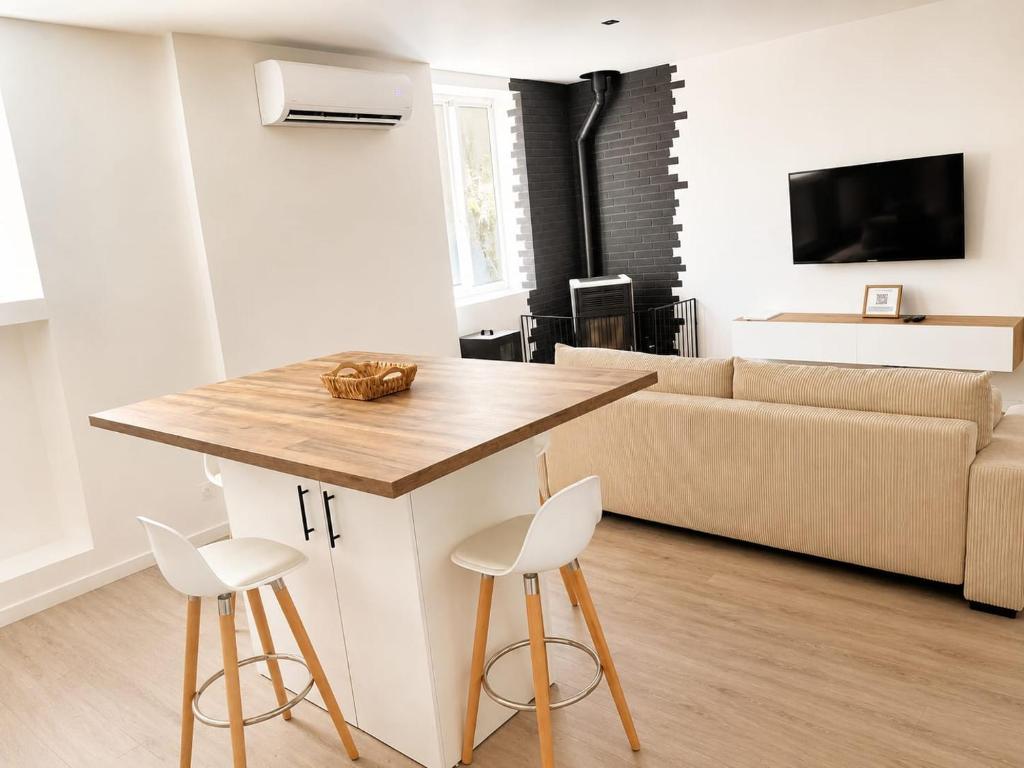 a kitchen and living room with a table and stools at L'immeuble du Monde Rose - Appartements neufs climatisés - classés 3 étoiles - Vic le Comte - Auvergne in Vic-le-Comte