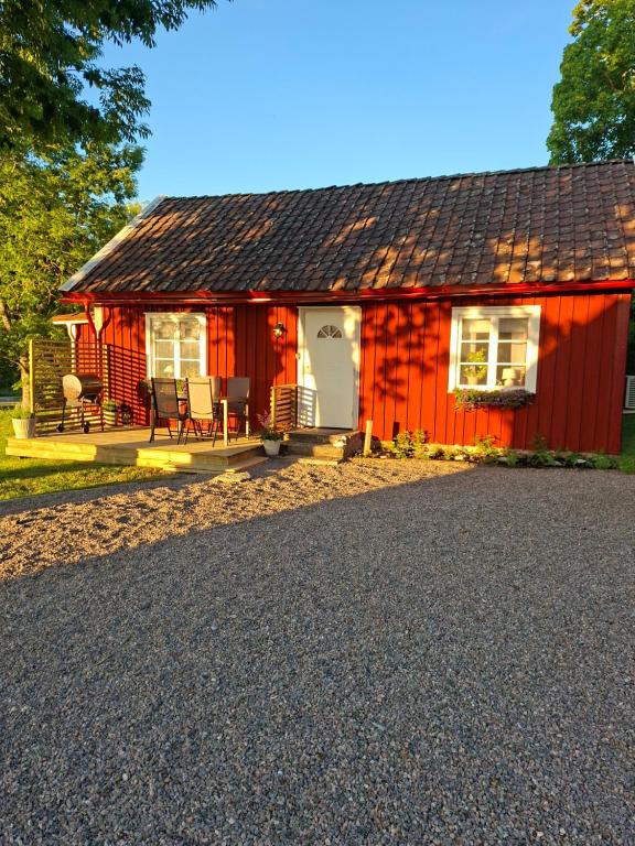 a red house with a gravel driveway in front of it at Fin torparstuga strax utanför Falköping. in Falköping