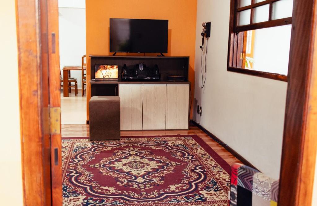 a living room with a television and a rug at Recanto D'Carvalho in Passa Quatro