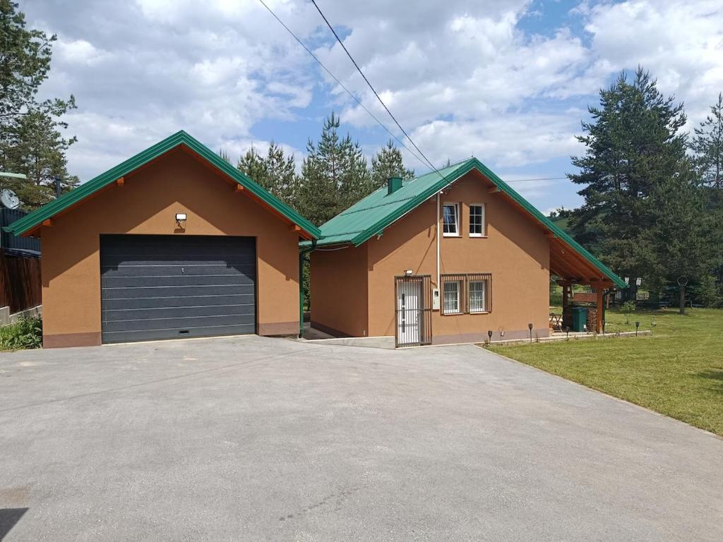 a house with a garage with a driveway at Planinska Kuća Nišićka visoravan in Ilijaš