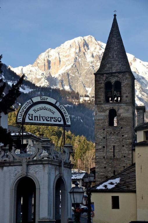 a building with a clock tower in front of a mountain at Appartamento in Hotel Residence Universo in Pré-Saint-Didier