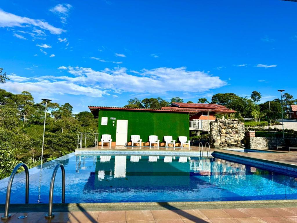 a swimming pool with chairs and a green building at Hosteria Arizona in Puyo