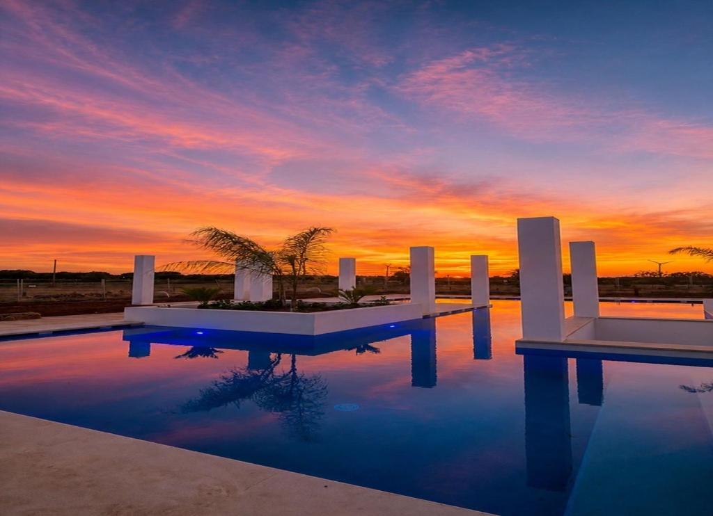 a swimming pool with a sunset in the background at Agriturismo Residence Molle con piscina in Carpignano Salentino