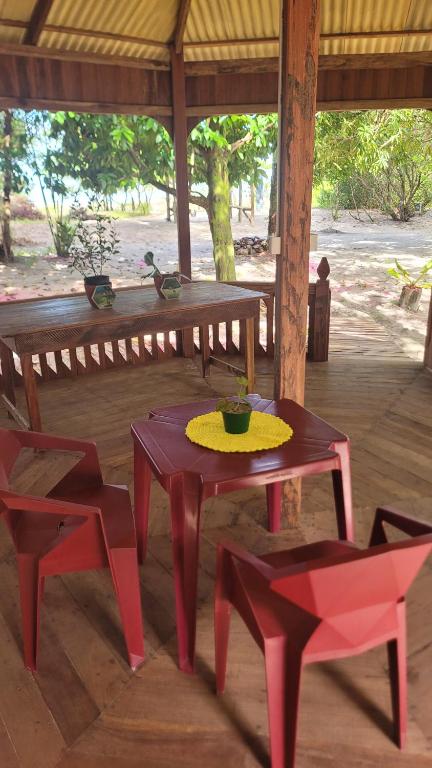 a picnic table and two red chairs in a pavilion at Hospedaria Ponta da Flexeira in Belém