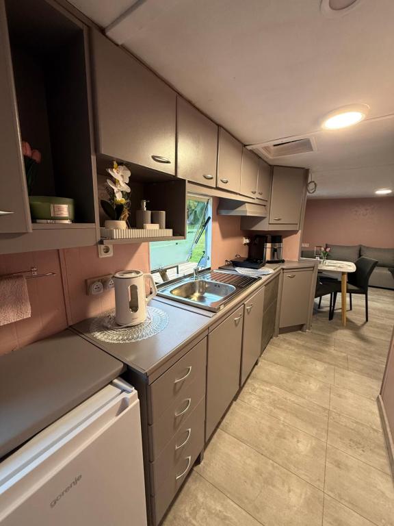 a kitchen with white cabinets and a sink and a table at SeaSoul Cottage in Zvejniekciems