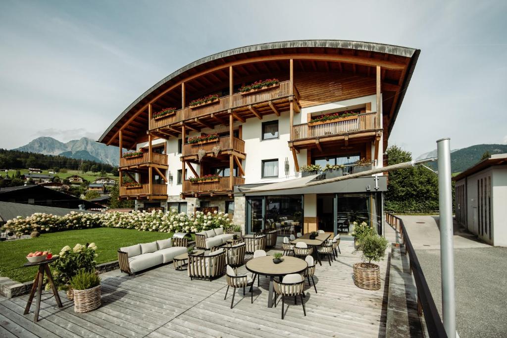 a building with a patio with tables and chairs at Sunnsait - Appartements für Genießer in Maria Alm am Steinernen Meer