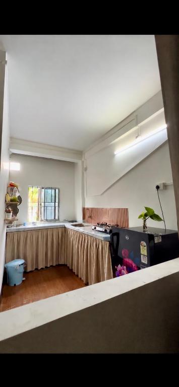 an empty room with a kitchen with a table at The Quiet Lantern Homestay in Sibsāgar