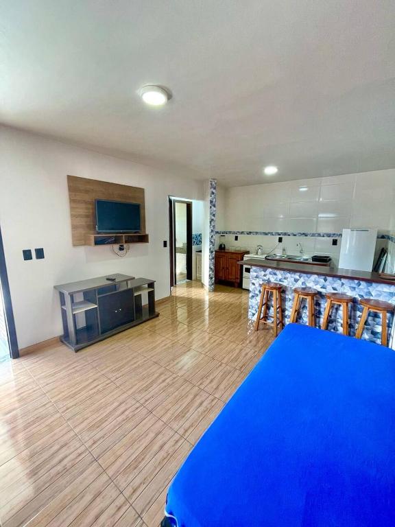 a living room with a kitchen and a blue table at 001 1 Dormitorio Centro Bombinhas 400 m da praia in Bombinhas