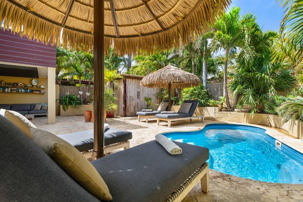 a patio with a swimming pool and an umbrella at Bamboo Bonaire by Boutique Bonaire Unique Resorts in Kralendijk