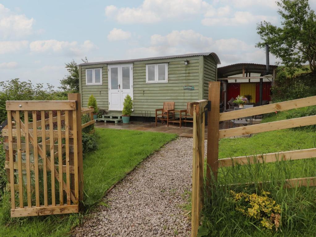a green caravan with a gate and a fence at The Journeyman Luxury Shepherds Hut in Barnoldswick
