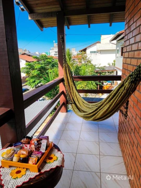 a hammock on a balcony with a table and food at 3 400m Centro de Bombinhas in Bombinhas