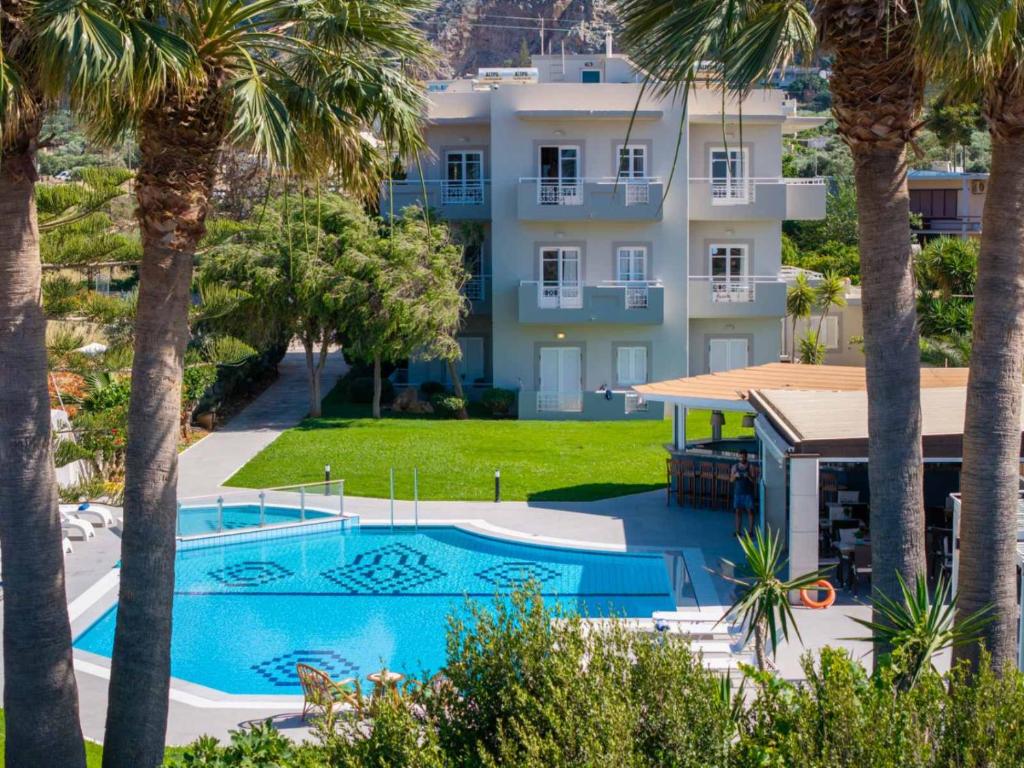 a view of a resort with a swimming pool and palm trees at Matthew's Place in Malia