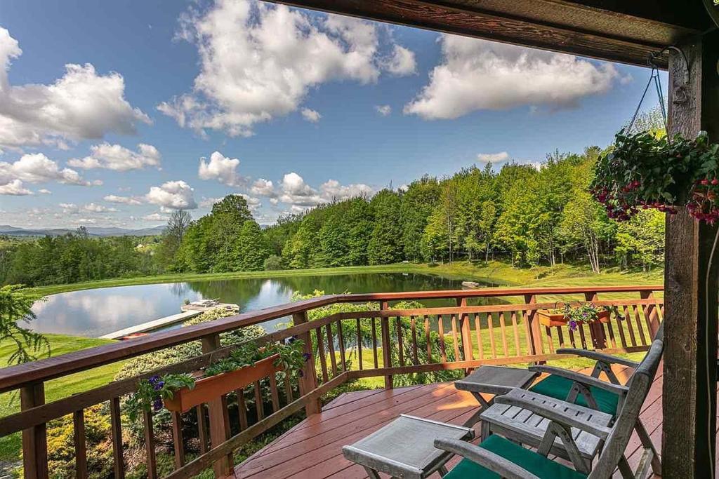 a deck with chairs and a view of a lake at Valley View in Stowe