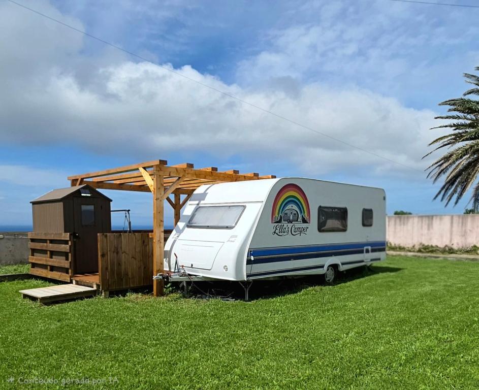 a white trailer with a rainbow on it parked in a field at Ella's Camper in Fontinha