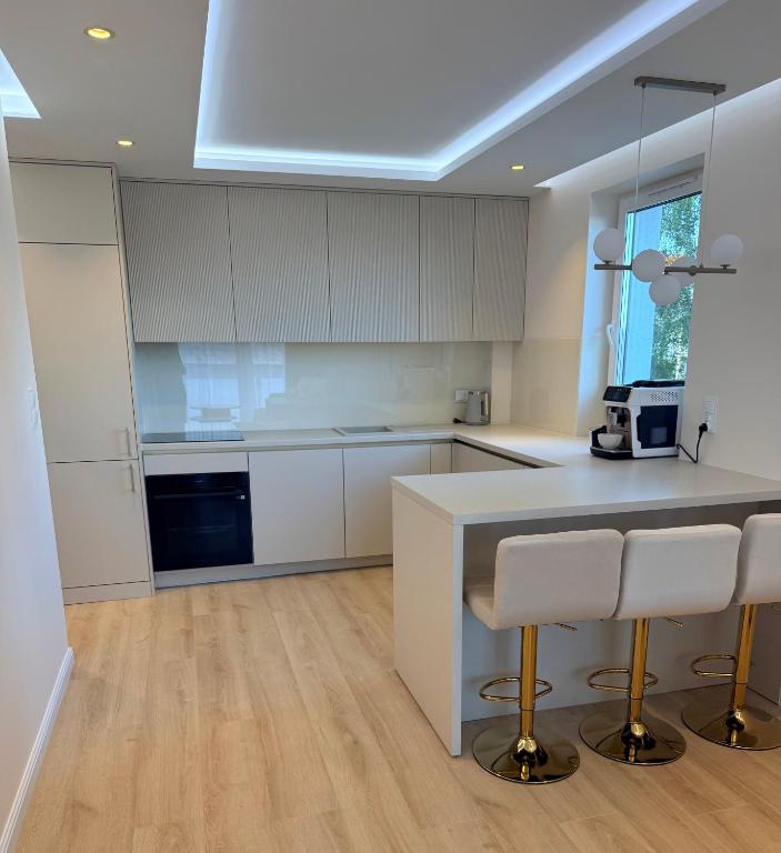 a kitchen with white cabinets and a counter with stools at Apartament Baltic Pearl in Ustka