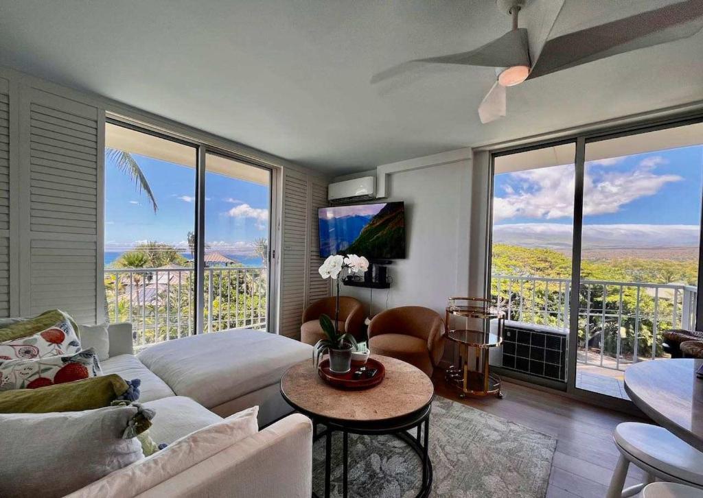 a living room with a couch and a table and some windows at Puako Penthouse 409 - Top Floor Unit - Pool in Puako
