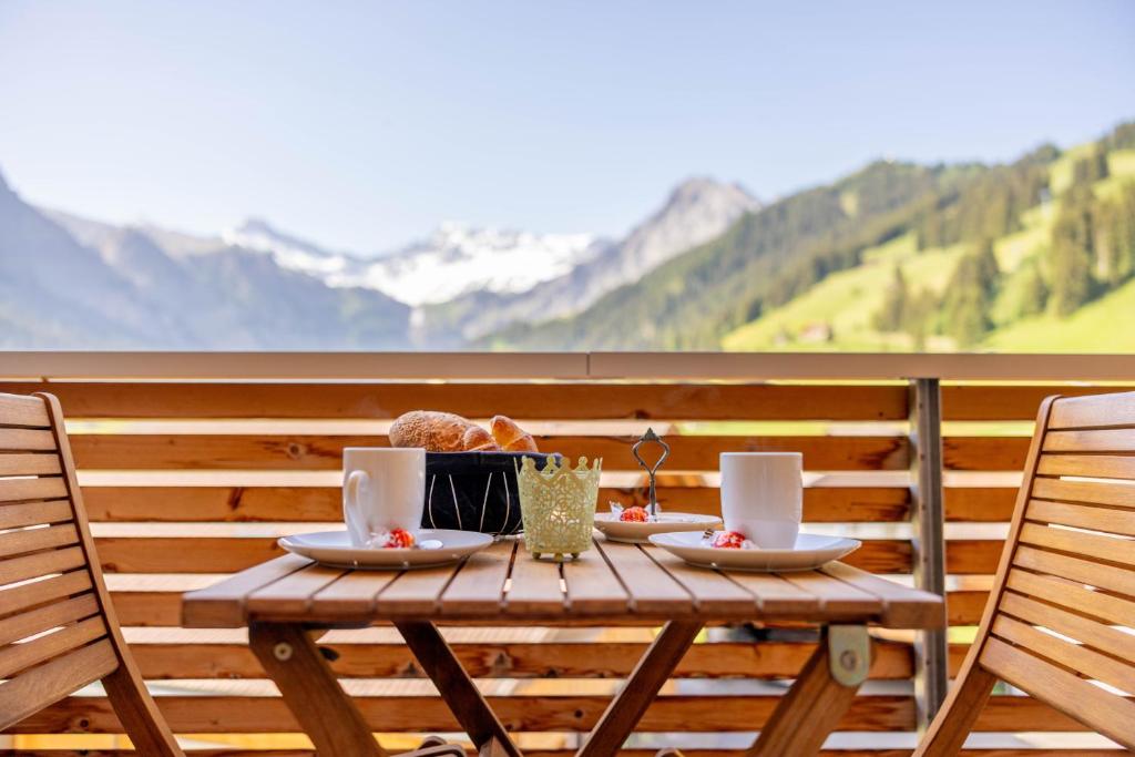 a wooden table with two plates of food on a balcony at Chuenislodge3 neu&stilvoll, 2Balkone, echtes Bijou mit top-Aussicht in Adelboden