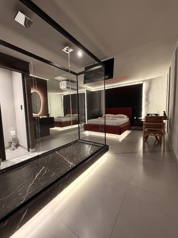 a large room with a glass shower and a bed at Khalifa Experience Motel in Itumbiara