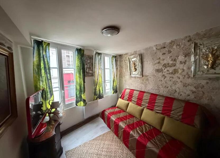 a living room with a red couch and windows at Maison atypique et confortable in Mamers