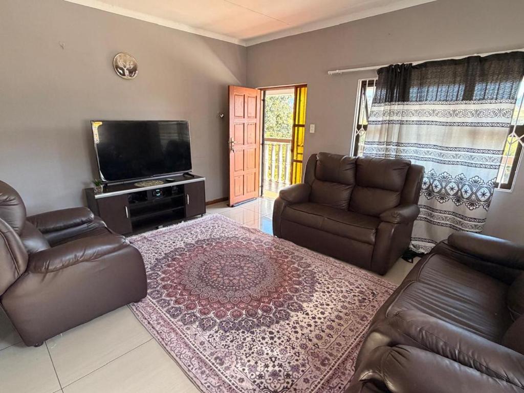 a living room with leather furniture and a flat screen tv at The Marina Suite in Mbabane