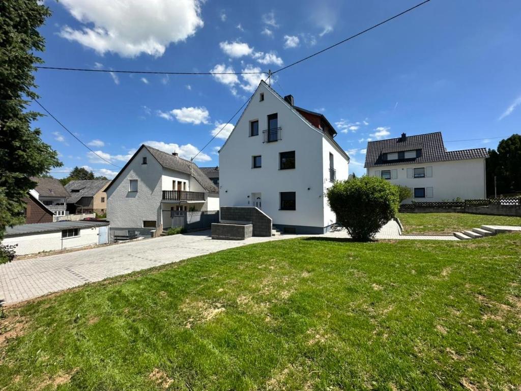 a white house with a green lawn in front of it at ME Apartments - Quartier Villmar in Villmar