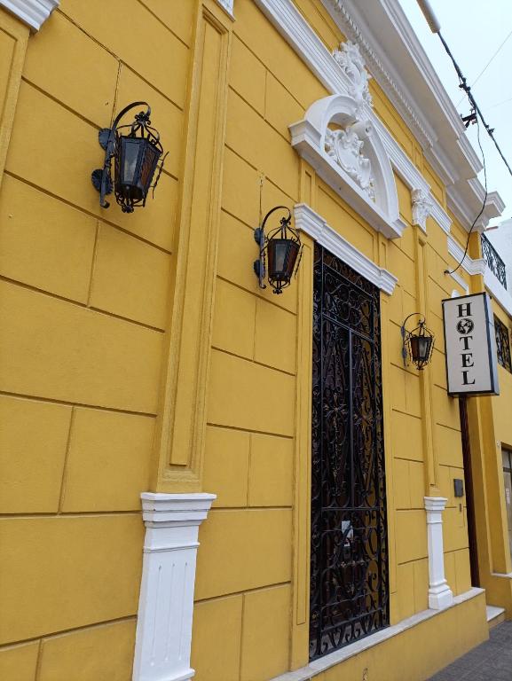 a yellow building with a door and a gate at Hotel America in Victoria