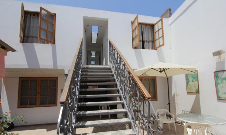 a staircase leading to a building with a table and an umbrella at NEW Hotel Casa del Profesor in Iquique