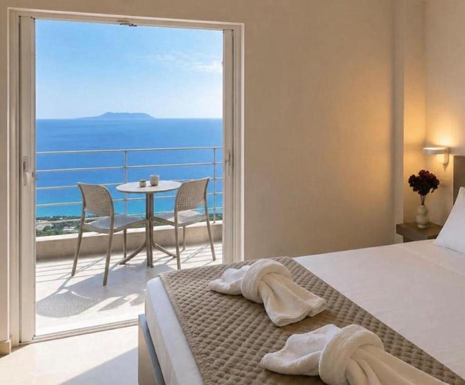 a bedroom with a bed and a balcony with a table at Nostos Palase in Dhërmi