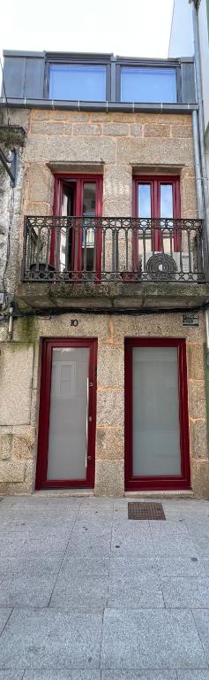 a building with red doors and a balcony at Mar De Pedra in Cangas de Morrazo