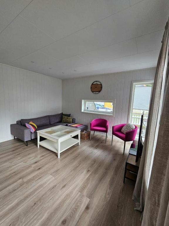 a living room with a couch and two pink chairs at Hillegård 6E in Lærdalsøyri