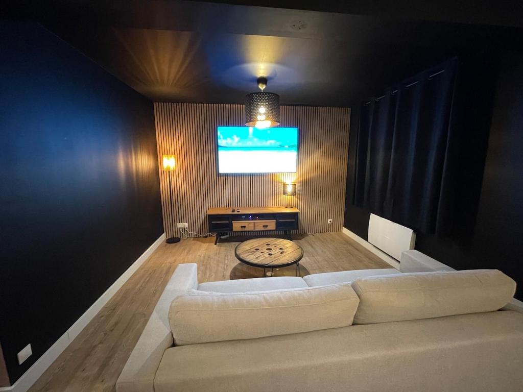 a living room with a white couch and a flat screen tv at La Guignicourtoise in Guignicourt